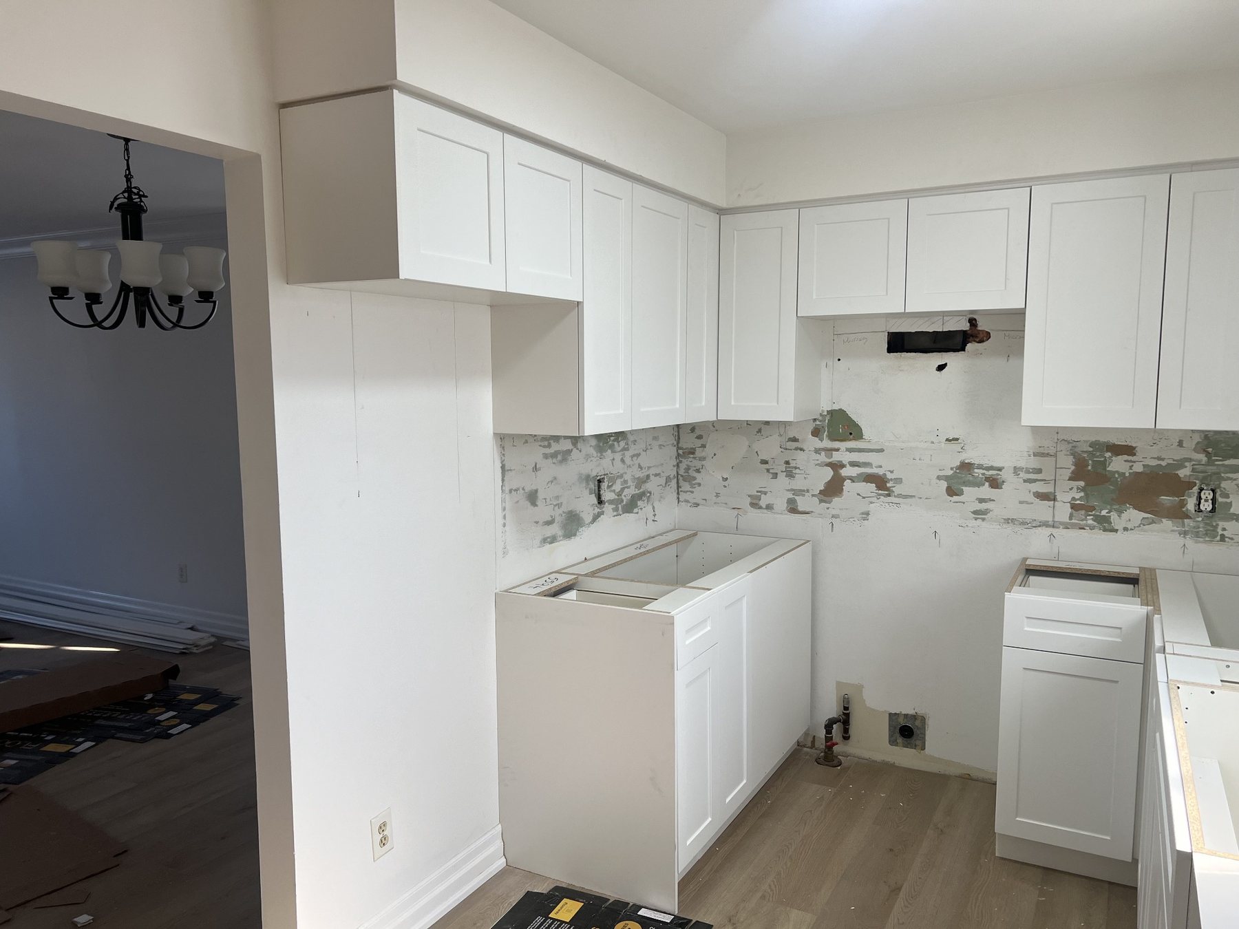 White upper kitchen cabinets refinished with black hardware and dark backsplash